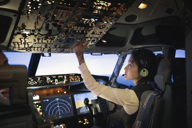 Rear view of a female pilot adjusting switches on the control panel while sitting inside cockpit. Woman operating the switches while flying an airplane. (Photo by Portra/Getty Images)