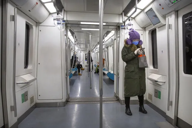 A woman wears safety goggles, a face mask, and rubber gloves as she rides a nearly empty subway train in Beijing, Friday, February 14, 2020. (Photo by Mark Schiefelbein/AP Photo)