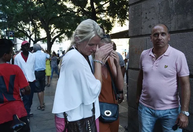 A woman is comforted as crowds flee from the scene after a white van jumped the sidewalk in the historic Las Ramblas district of Barcelona, Spain, crashing into a summer crowd of residents and tourists Thursday, August 17, 2017. According to witnesses the white van swerved from side to side as it plowed into tourists and residents. (Photo by Giannis Papanikos/AP Photo)