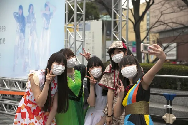 Fans wearing masks pose for photos before the start of a concert by Japanese girl group Perfume outside Tokyo Dome in Tokyo, Tuesday, February 25, 2020. Japan's Prime Minister Shinzo Abe said Tuesday that new measures like companies letting their employees work from home and hospitals expanding their capacity to treat many patients will determine if Japan could control its coronavirus outbreak. (Photo by Jae C. Hong/AP Photo)