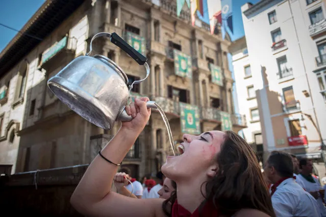 A woman drinks before the Riau-Riau procession of the San Fermin Festival on July 6, 2016 in Pamplona. The Riau-Riau is a procession held on 6 July in which members of the city council parade from the City Hall to a nearby chapel dedicated to Saint Fermin, on July 6, 2016. (Photo by Pedro Armestre/AFP Photo)