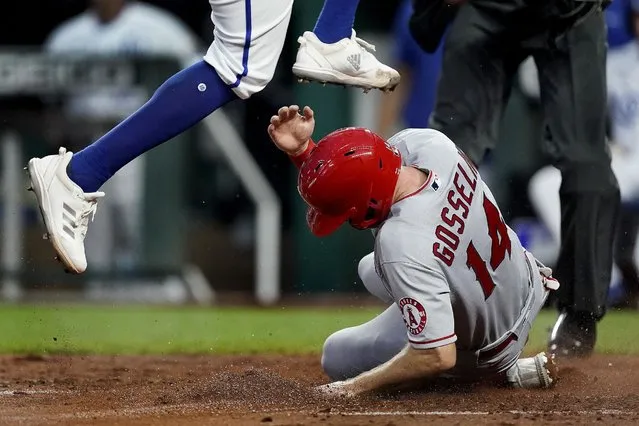 Kansas City Royals relief pitcher Amir Garrett leaps over Los Angeles Angels' Phil Gosselin (14) after Gosselin scored on Garrett's wild pitch during the fifth inning of a baseball game Tuesday, July 26, 2022, in Kansas City, Mo. (Photo by Charlie Riedel/AP Photo)
