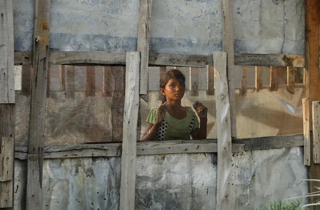A Rohingya refugee girl looks through a mesh window at a camp set up for the refugees on the outskirts of Jammu, India, Wednesday, August 16, 2017. A day after the U.N. chief voiced concern about Indian plans to potentially deport tens of thousands of Muslim Rohingya refugees, an Indian government official said Wednesday that authorities are only working to identify those who fled persecution in neighboring Myanmar, not expel them. An estimated 40,000 Rohingya Muslims have taken refuge in various parts of India, though fewer than 15,000 are registered with the U.N. High Commissioner for Refugees. (Photo by Channi Anand/AP Photo)