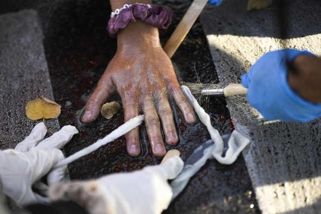 Police officers remove the glued hand of a climate activist from a road during a climate protest in Berlin, Germany, Monday, September 18, 2023. Activists of the “Last Generation”, Letzte Generation, blocked streets in Berlin Tuesday to protest against the climate policies of the German government.(Photo by Markus Schreiber/AP Photo)