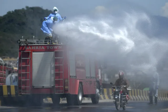 Workers wearing protective gear spray disinfectant on a street at a residential area during a government-imposed nationwide lockdown as a preventive measure against the COVID-19 coronavirus, in Islamabad, Pakistan on March 29, 2020. (Photo by Aamir Qureshi/AFP Photo)