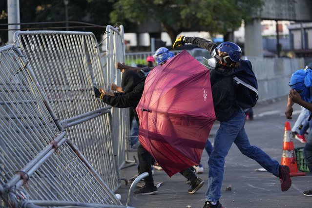 Demonstrators pull down a barricade during a protest against a recently approved mining contract between the government and Canadian mining company First Quantum, outside the National Assembly in Panama City, Monday, October 23, 2023. (Photo by Arnulfo Franco/AP Photo)