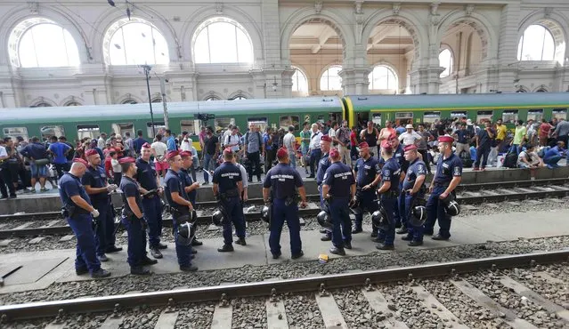 Hungarian policemen stand in front of migrants on a platform at the Keleti train station in Budapest, Hungary, September 3, 2015 as Hungarian police withdrew from the gates after two days of blocking their entry. (Photo by Laszlo Balogh/Reuters)