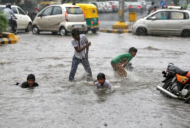 Boys play on a waterlogged road during rains in Ahmedabad, India, July 27, 2016. (Photo by Amit Dave/Reuters)