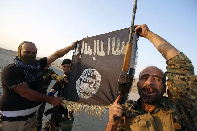 Iraqi Shiite militia fighters hold the Islamic State flag as they celebrate after breaking the siege of Amerli by Islamic State militants, September 1, 2014. (Photo by Youssef Boudlal/Reuters)