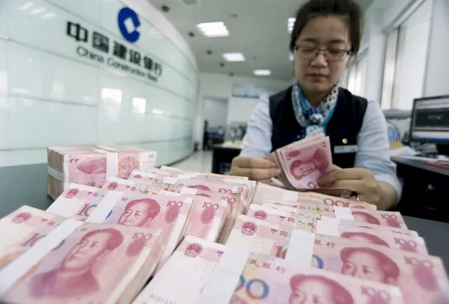 A clerk counts Chinese 100 yuan banknotes at a branch of China Construction Bank in Hai'an, Jiangsu province in this June 10, 2014 file photo. China devalued its currency on Tuesday after a run of poor economic data, a move it billed as a free-market reform but which some suspect could be the beginning of a longer-term slide in the exchange rate. (Photo by Reuters/China Daily)