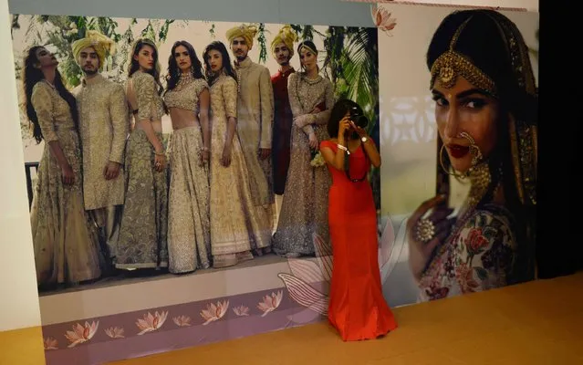An Indian woman clicks a picture outside a designer stall during the Vogue Wedding Show 2016, in New Delhi on August 5, 2016. A 3-day opulent wedding exhibition showcasing the latest and exclusive wedding services and over 50 coveted brands from the bridal world, will be held from August 5-7 2016. (Photo by Money Sharma/AFP Photo)