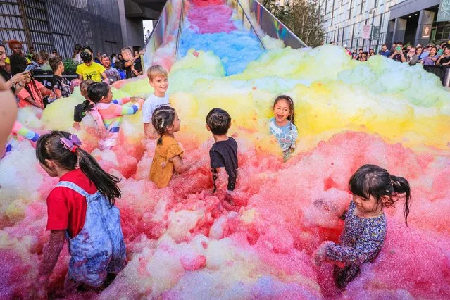 Children have fun in the foam in London on September 3, 2022. People interact with “Island of Foam: Version XVIII”, a colourful, constantly changing foam installation. The installation is a UK premiere from German artist Stephanie Luning (who is operating the “foam cannon” at the top of the stairs), transforming Greenwich Peninsula with mountains of rainbow coloured foam. (Photo by Imageplotter/Alamy Live News)