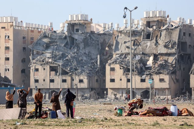 Palestinians in the Qatari-funded Hamad Town residential complex in Khan Yunis in the southern Gaza Strip on December 2, 2023, walk in front of the destroyed buildings as they flee their homes after an Israeli strike hit 7 towers in the city of Hamad. A temporary truce between Israel and Hamas expired on December 1, with the Israeli army saying combat operations had resumed, accusing Hamas of violating the operational pause. (Photo by Ahmed Zakot/SOPA Images/Rex Features/Shutterstock)