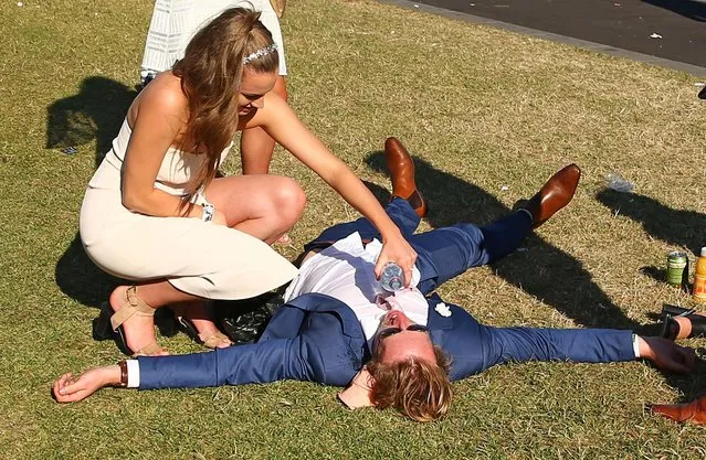 A racegoer is given some water as he lays on the ground following 2017 Stakes Day at Flemington Racecourse on November 11, 2017 in Melbourne, Australia. (Photo by Scott Barbour/Getty Images)