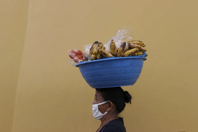 Guillerma Torres, wearing a face mask to curb the spread of the new coronavirus, carries a basket of fruit on her head to sell, on a street in Tegucigalpa, Honduras, Thursday, June 18, 2020. The hospitalization Wednesday of Honduras' president with COVID-19 and pneumonia has drawn attention to another country struggling under the pandemic's strain as cases rise exponentially in the capital. (Photo by Elmer Martinez/AP Photo)