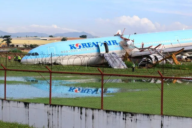 A Korean Air passenger plane lies its belly on the runway at the airport in Cebu City, central Philippines on October 24, 2022, after it overshot the runway late October 23 while landing in bad weather. (Photo by Alan Tangcawan/AFP Photo)
