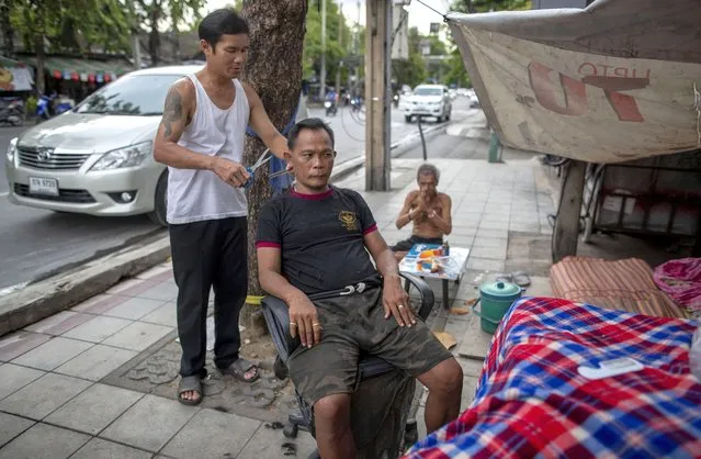 A man receives a haircut from a roadside barber in Bangkok, Thailand, Tuesday, June 23, 2020. Daily life in the capital is resuming to normal as the Thai government continues to ease restrictions related to running business and activities that were imposed weeks ago to combat the spread of COVID-19. (Photo by Gemunu Amarasinghe/AP Photo)