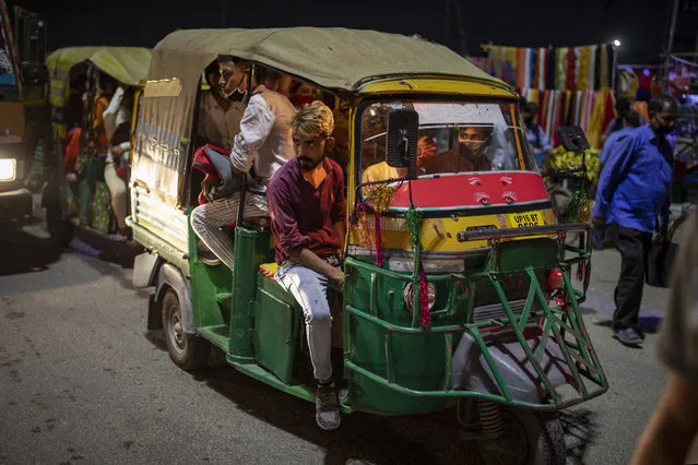 Commuters, some of them wearing masks as a precaution against the coronavirus ride an auto-rickshaw in Noida, outskirts of New Delhi, India, Thursday, July 16, 2020. (Photo by Altaf Qadri/AP Photo)