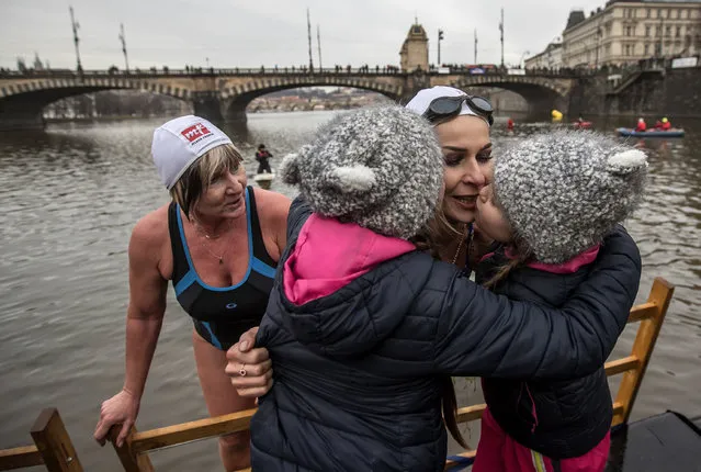 Girls kiss a swimmer as she climbs out of the Vltava river at the traditional Christmas winter swimming competition named in memory of Alfred Nikodem in Prague, Czech Republic, 26 December 2017. Enthusiast swimmers every year brave the cold waters of the Vltava river for a swim on 26 December. This year 369 swimmers took part in water temperatures of 4.5 degrees Celsius. (Photo by Martin Divisek/EPA/EFE)