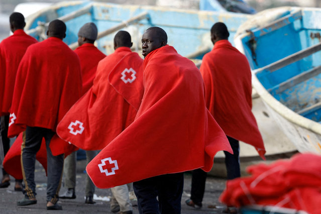 A group of migrants wait to be assisted by the Red Cross after disembarking at the Port of Arguineguin, on the island of Gran Canaria, Spain on February 8, 2024. (Photo by Borja Suarez/Reuters)