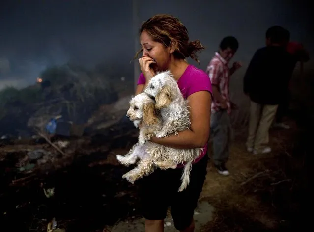 A woman leaves the site of a fire on the outskirts of Tijuana, Mexico. (Photo by Guillermo Arias/Associated Press)