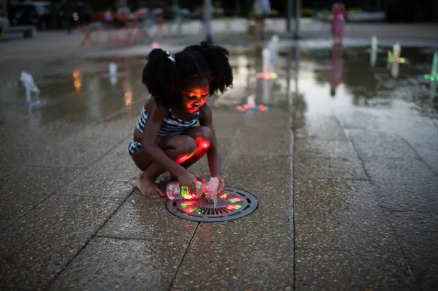 Meaghan Wallace, 3, of DC, fills a water bottle at the Canal Park sprayground on July 9, 2016. The sprayground at Canal Park is an interactive water fountain with programmable water jets embedded below the pavement that are illuminated in many colors. The park at 200 M St. SE was built on the site of the historic Washington Canal in the heart of DC's Captiol Riverfront neighborhood. It (Photo by Sarah L. Voisin/The Washington Post)