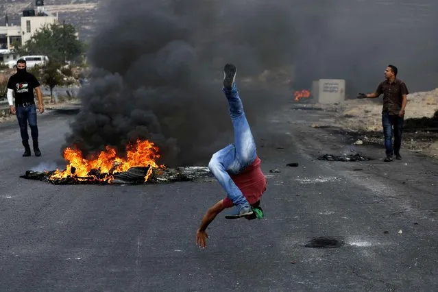 A Palestinian protester taunts Israeli borderguards during clashes next to the Jewish settlement of Beit El, north of Ramallahon October 19, 2015. More than two weeks of unrest have raised warnings of the risk of a full-scale Palestinian uprising, while some Israeli politicians have urged residents to arm themselves to fend off the threat of stabbings and gun assaults. (Photo by Abbas Momani/AFP Photo)