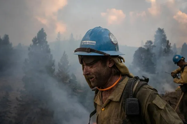 Kirk McDusky, a member of the Prineville Hotshot Crew, walks past smoke rising from the Brattain Fire in the Fremont National Forest in Paisley, Oregon, U.S., September 18, 2020. (Photo by Adrees Latif/Reuters)