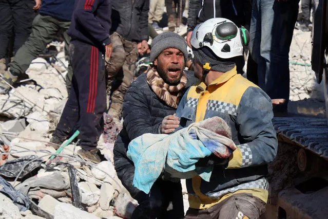 A man reacts as the body of his baby pulled out from the rubble, is taken away by a Syrian White Helmet rescue worker, in the town of Harim in Syria's rebel-held northwestern Idlib province on the border with Turkey, on February 8, 2023, two days after a deadly earthquake that hit Turkey and Syria. The death toll from the massive earthquake that struck Turkey and Syria on February 6 rose above 8,300, official data showed, with rescue workers on February 8 still searching for trapped survivors. (Photo by Mohammed Al-Rifai/AFP Photo)