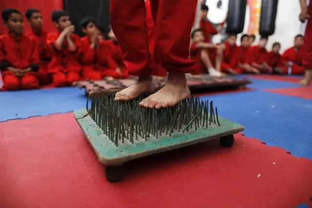 A Palestinian boy stands on a bed of nails during a class at the Red Dragon martial arts club in Beit Lahiya in the northern Gaza Strip March 29, 2013. Dozens of boys from eight to 15 years of age are part of the club. (Photo by Suhaib Salem/Reuters)