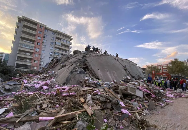 Rescue workers try to save people trapped in the debris of a collapsed building, in Izmir, Turkey, Friday, October 30, 2020. A strong earthquake struck Friday in the Aegean Sea between the Turkish coast and the Greek island of Samos, killing several people and injuring hundreds amid collapsed buildings and flooding, officials said. (Photo by Ismail Gokmen/AP Photo)