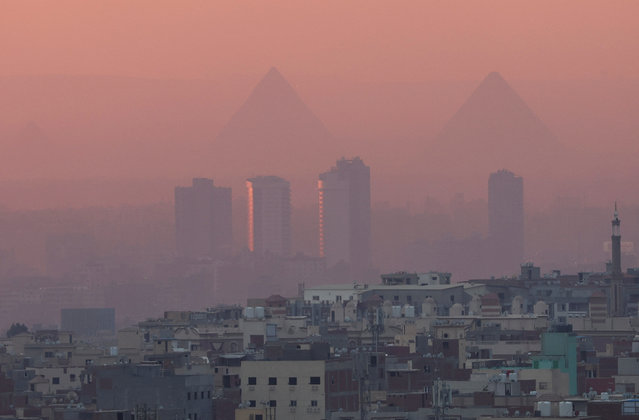 A view of old houses with hotels and the Great Pyramids during sunset with fog from air pollution over the Egypt's capital of Cairo, Egypt on February 5, 2023. (Photo by Amr Abdallah Dalsh/Reuters)
