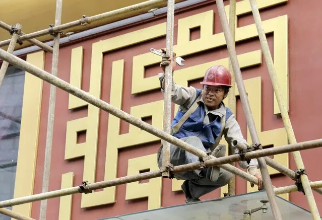 A laborer works on scaffolding at a construction side in central Beijing, China, October 16, 2015. China's economic growth eased to 6.9 percent in the third quarter from a year earlier, beating expectations but still the slowest since the global financial crisis, putting pressure on policymakers to roll out more support measures as fears of a sharper slowdown spook investors. (Photo by Jason Lee/Reuters)