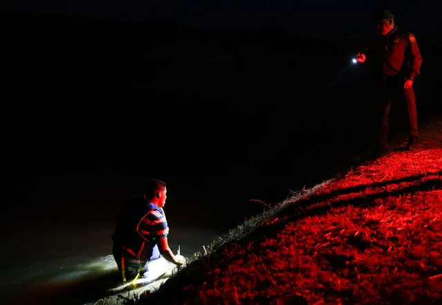An immigrant who jumped into a canal in an effort to escape capture after illegally crossing the Mexico-U.S. border gives up and turns himself in to a border patrol agent in the Rio Grande Valley sector, near McAllen, Texas, U.S., April 5, 2018. (Photo by Loren Elliott/Reuters)