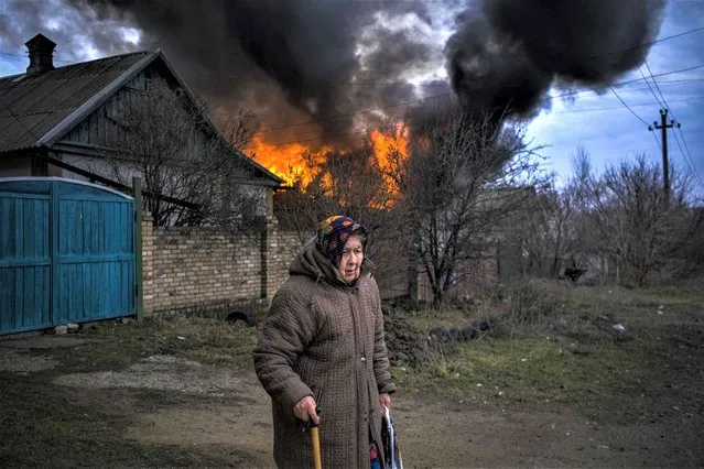 An elderly woman stands near a burning building following shelling in Kostyantynivka, Donetsk region, on March 15, 2023, amid the Russian invasion of Ukraine. (Photo by Sergey Shestak/AFP Photo)