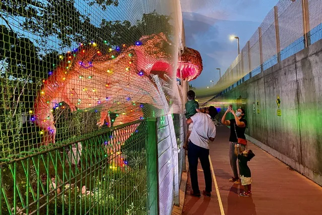 A family poses for photos near a dinosaur exhibits along the Changi Jurassic Mile as it is light up for Christmas near Changi airport in Singapore on December 8, 2020. (Photo by Tim Chong/Reuters)