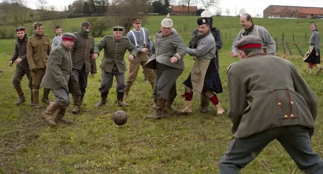 Re-enactors, from various living history groups, are dressed in World War I British and German uniforms as they kick around a soccer ball during a re-enactment of the 1914 Christmas Truce in Ploegsteert, Belgium on Saturday, December 20, 2014. During that first Christmas Day in World War I, something magical happened. Soldiers who had been killing each other by the tens of thousands for months climbed out of their muddy trenches to seek a shred of humanity amid the horrors of war. (Photo by Virginia Mayo/AP Photo)