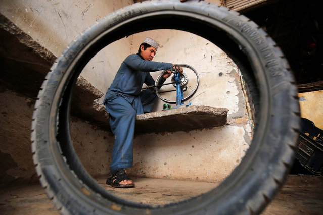 A Pakistani boy repairs a motorbike wheel on a workshop as the world observes Universal Children's Day in Peshawar, Pakistan, 20 November 2020. Universal Children's Day is observed every year on 20 November as a day of worldwide fraternity and understanding between children. (Photo by Bilawal Arbab/EPA/EFE)
