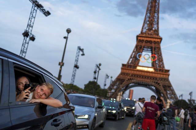 Passengers in the back of a taxi film themselves as they leave the Eiffel Tower decorated with the Olympic rings ahead of the 2024 Summer Olympics, in Paris, July 17, 2024. (Photo by David Goldman/AP Photo)