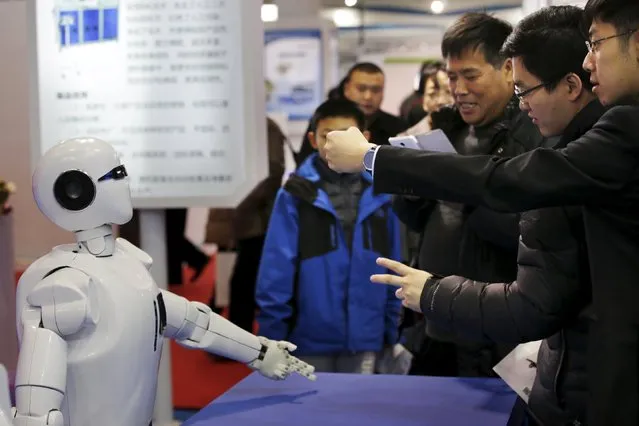 Visitors gesture to a KINGER Robot at the World Robot Exhibition during the World Robot Conference in Beijing, China, November 24, 2015. (Photo by Jason Lee/Reuters)