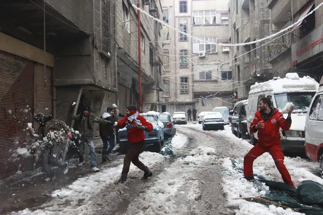 Civilians and members of the Syrian Arab Red Crescent play with snow in the Duma neighbourhood of Damascus January 7, 2015. A storm buffeted the Middle East with blizzards, rain and strong winds on Wednesday, keeping people at home across the region and raising concerns for Syrian refugees facing freezing temperatures in flimsy shelters. Picture taken January 7, 2015. (Photo by Badra Mamet/Reuters)