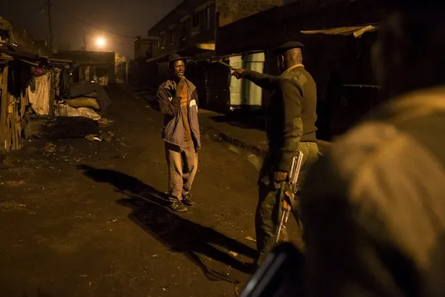 A police officer gestures to a man on a street in Korogocho during a night patrol in Nairobi, Kenya, October 30, 2015. Around 2 million people live in the shantytowns packed in around Kenya's capital. Crime is high amid chronic unemployment levels, while basic services and sanitation are scarce. Residents try to make the best of things, eking out a living and picking up work where they can. (Photo by Siegfried Modola/Reuters)