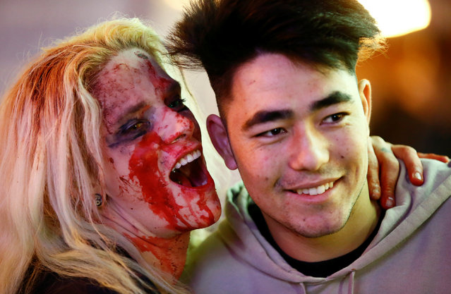 A tourist poses with a woman dressed as a zombie during the so-called “Zombie walk” through the western German city of Essen on Halloween Day, October 31, 2016. (Photo by Wolfgang Rattay/Reuters)