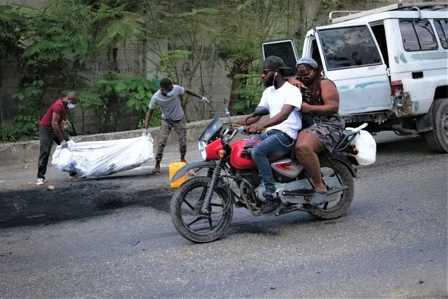 Two men carry the cremated body of a person in Port-au-Prince, Haiti, 02 May 2023. At least five people were killed on 02 May 2023 by the population in Petion-ville, Port-au-Prince, for being alleged members of the Ti Makak armed group, dismantled a few weeks ago by the National Police. (Photo by Johnson Sabin/EPA/EFE)