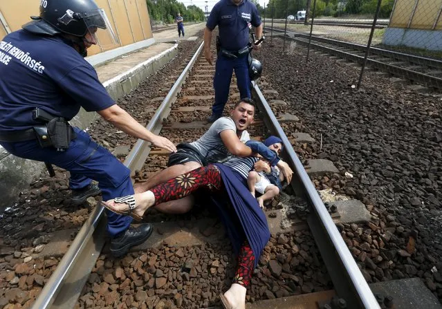 Hungarian policemen stand by the family of migrants as they wanted to run away at the railway station in the town of Bicske, Hungary, September 3, 2015. (Photo by Laszlo Balogh/Reuters)