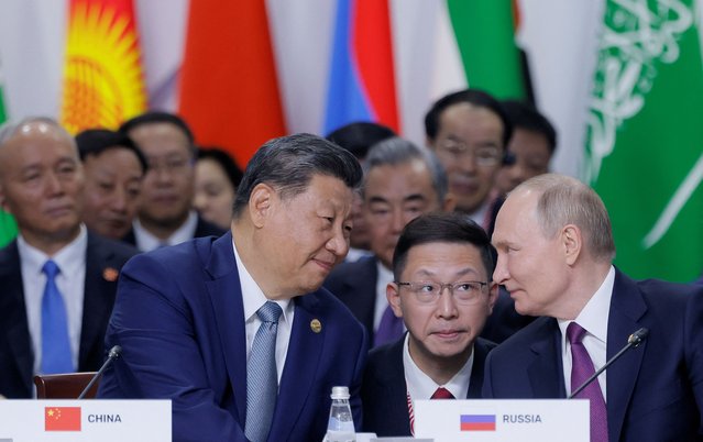 Russian President Vladimir Putin and Chinese President Xi Jinping speak during a plenary session in the outreach/BRICS Plus format at the BRICS summit in Kazan on October 24, 2024. (Photo by Maxim Shemetov/Pool via AFP Photo)