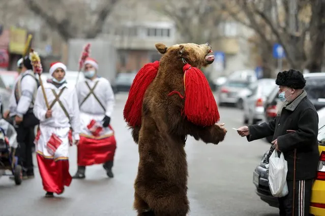 A street performer dressed as a bear collects donations from passersby in central Bucharest, Romania on December 2, 2020. (Photo by Octav Ganea/Reuters)