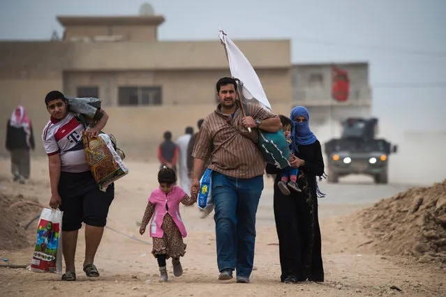 Iraqis carry white flags as they flee to an area held by the Iraqi Special Forces 2nd division in the Samah neighbourhood of Mosul on November 15, 2016, during an ongoing operation against Islamic State (IS) group jihadists. Hundreds of people used the opportunity to get out of harms way during a period of relative calm on the frontline neighbourhoods of eastern Mosul. (Photo by Odd Andersen/AFP Photo)