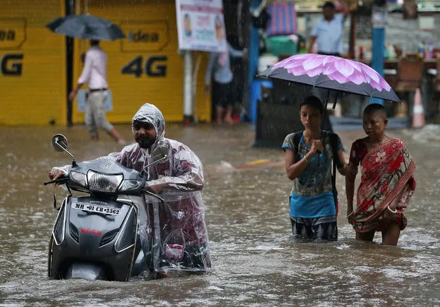 People wade through a waterlogged street after heavy rains in Mumbai, India July 3, 2018. (Photo by Francis Mascarenhas/Reuters)