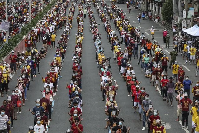 Thousands of Catholic devotees line up as they celebrate the feast day of the Black Nazarene  at the Minor Basilica of the Black Nazarene in downtown Manila, Philippines, Saturday January 9, 2021. Hundreds of church workers and police were spread around the area to maintain order and enforce strict social distancing health protocols. The annual procession has been cancelled amid the threat of the ongoing COVID-19 pandemic in one of Asia's biggest religious events. (Photo by Gerard Carreon/AP Photo)